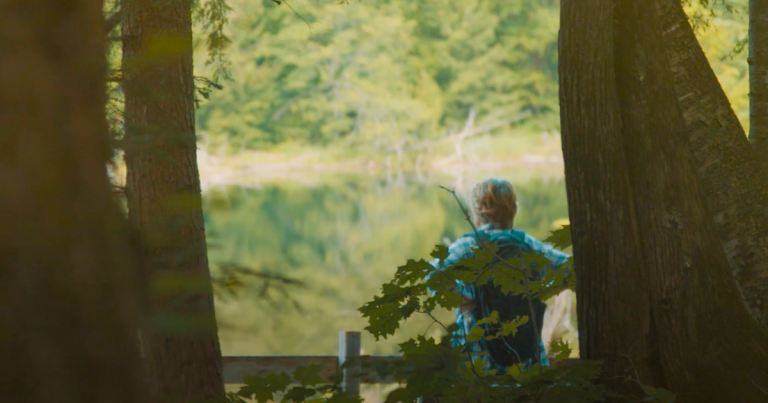 Une personne qui regarde au loin sur le bord d'un lac